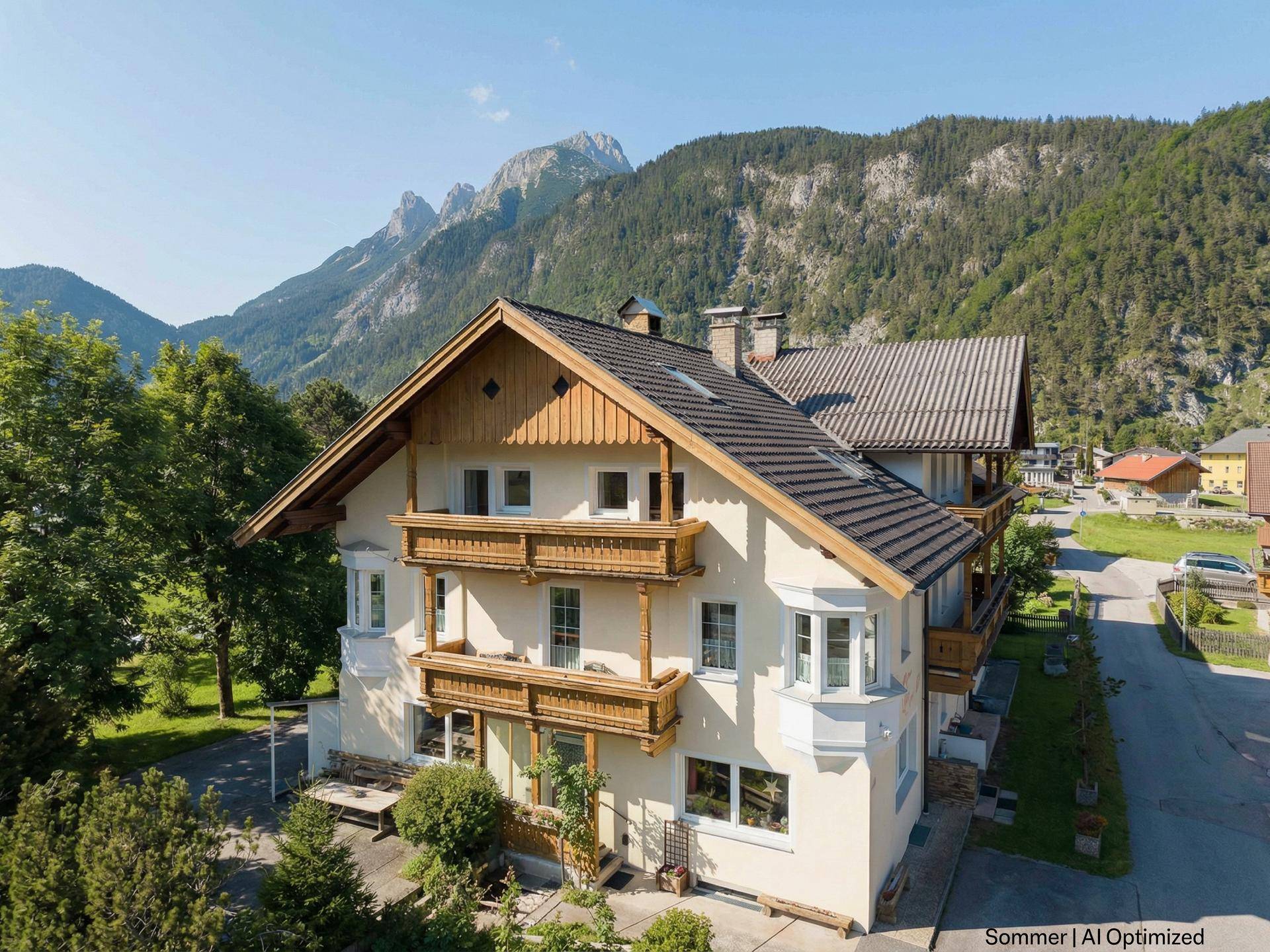 Traditionelles Gebäude mit Holzbalkonen und Bergblick in einer alpinen Umgebung.