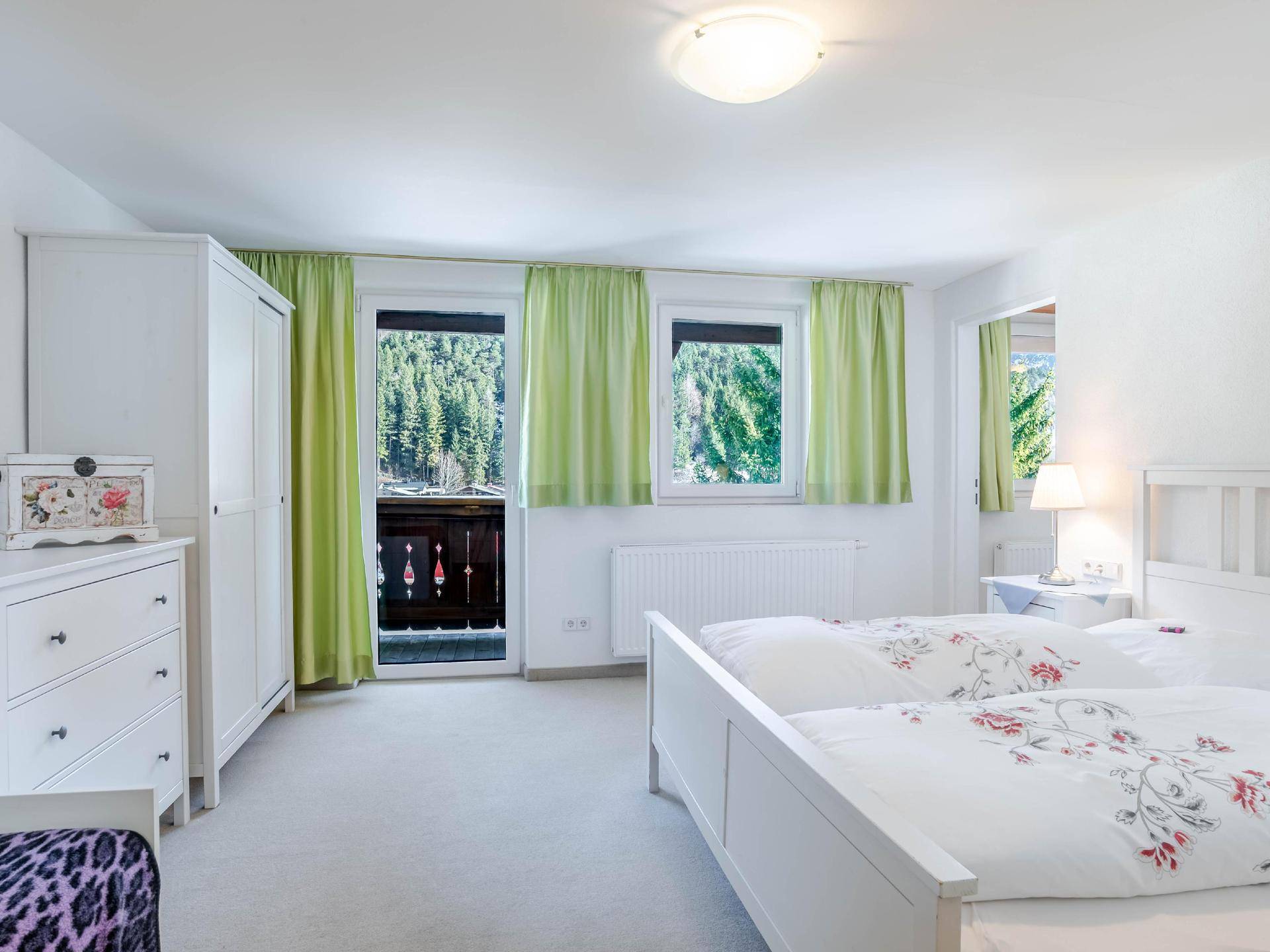 Gemütliches Schlafzimmer mit zwei Einzelbetten, Kleiderschrank und Balkonzugang mit Bergblick.