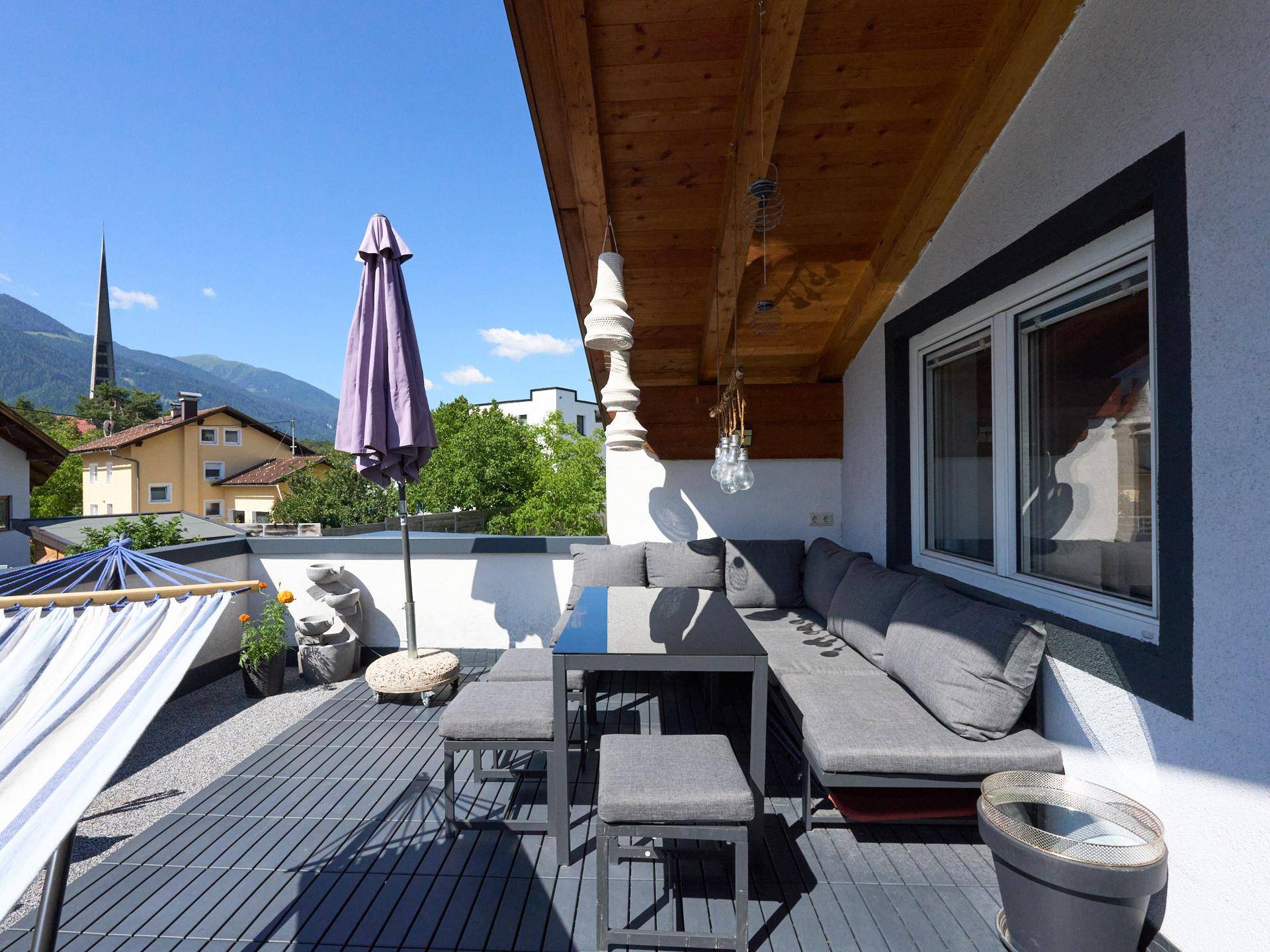 Sonnige Terrasse mit bequemen Outdoor-Möbeln und Blick auf die Umgebung.