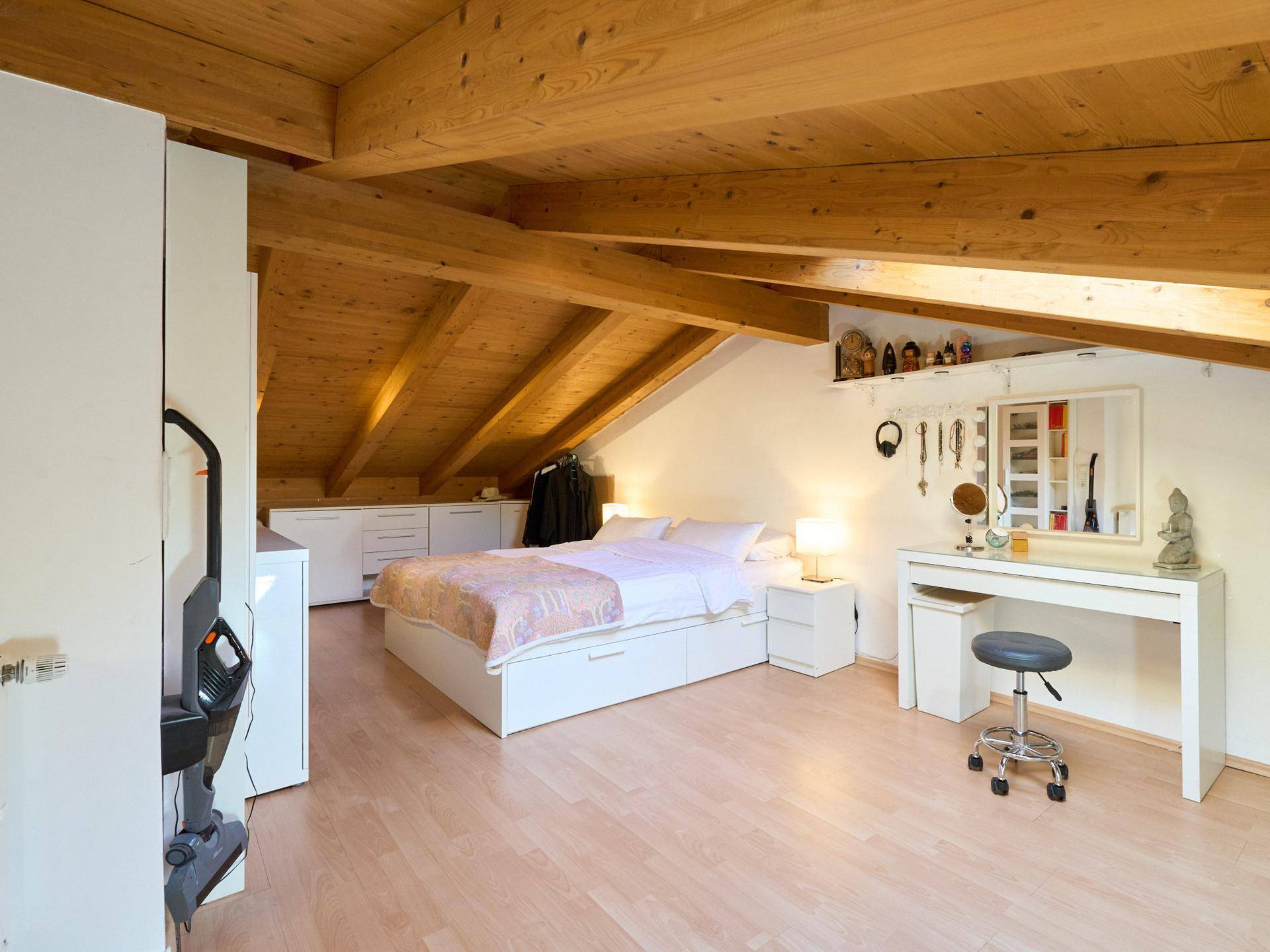 Gemütliches Schlafzimmer im Dachgeschoss mit Holzbalken und Dachschrägen.