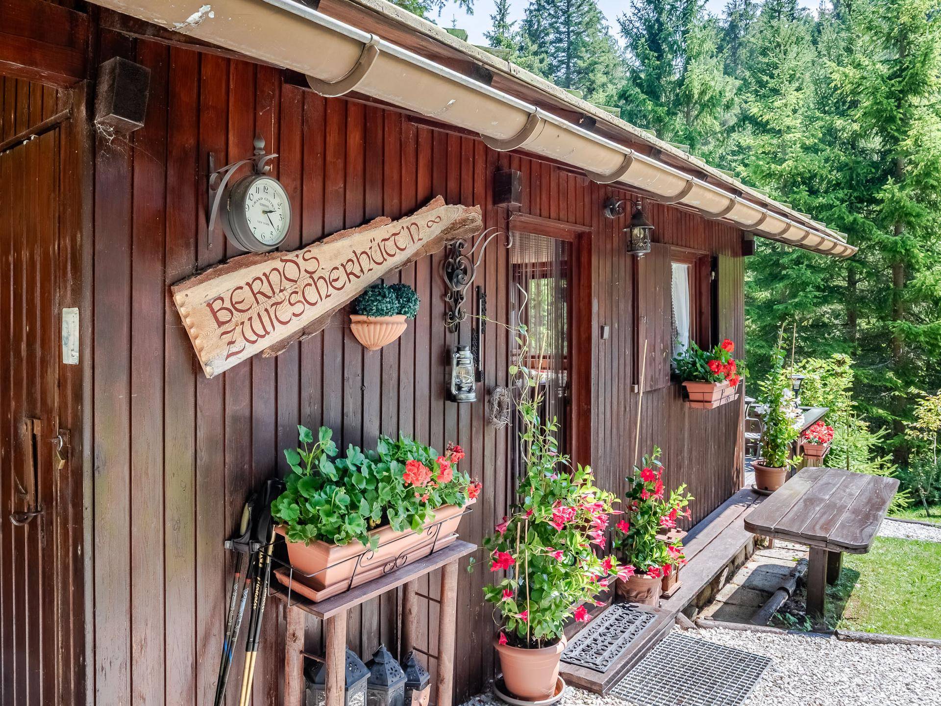 Rustikale Holzhütte mit traditioneller Dekoration, Blumenkästen und einem personalisierten Schild.