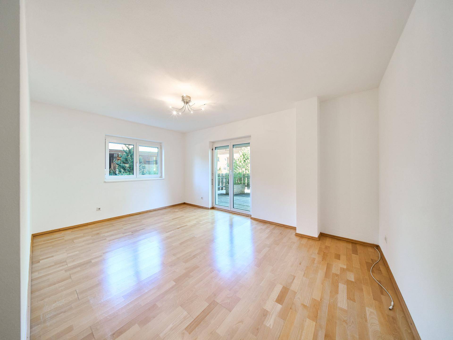 Helles Schlafzimmer mit Holzboden und direktem Zugang zu einem Balkon oder einer Terrasse.