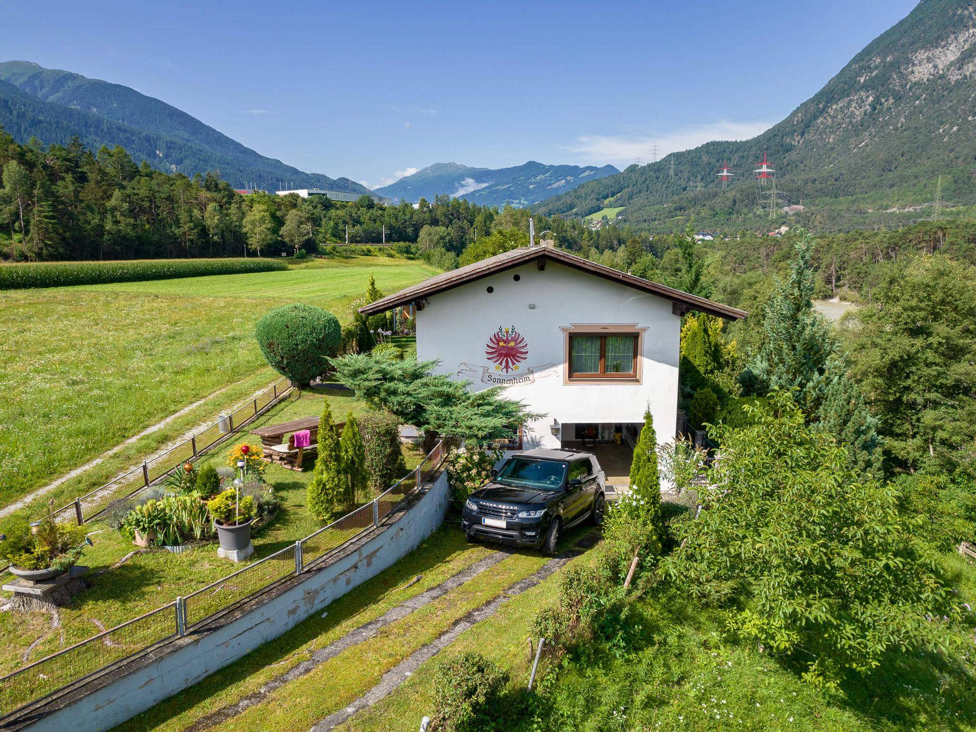Luftaufnahme des Hauses in ländlicher Umgebung mit weiten Feldern und Bergblick.