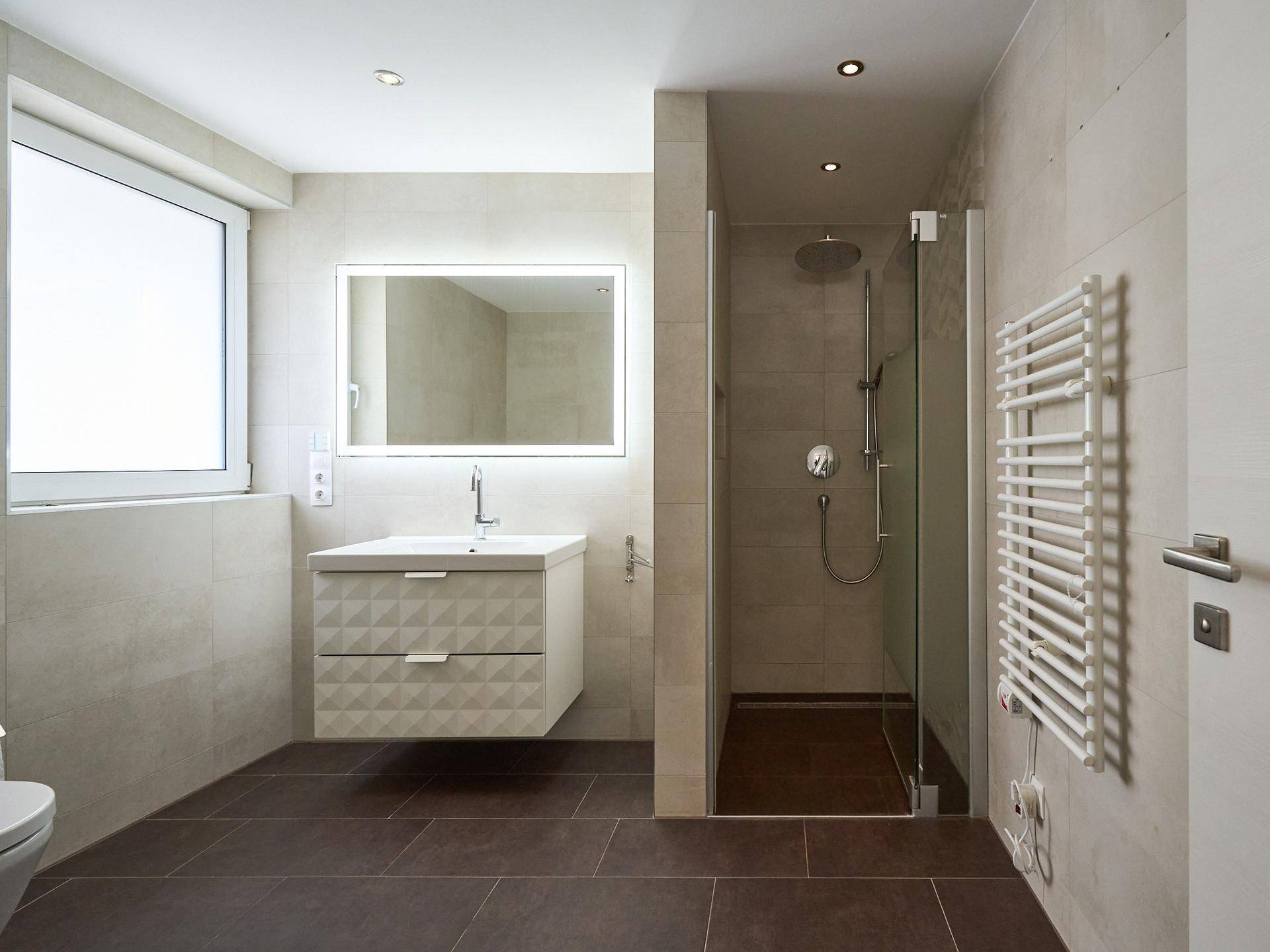 Modernes Badezimmer mit ebenerdiger Dusche, Waschtisch und beheiztem Handtuchhalter.