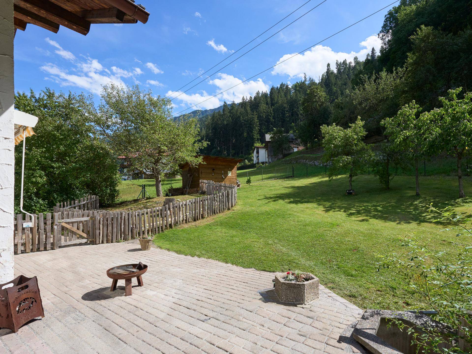 Geräumige Terrasse mit Blick auf den weitläufigen Garten und die umliegende Berglandschaft.