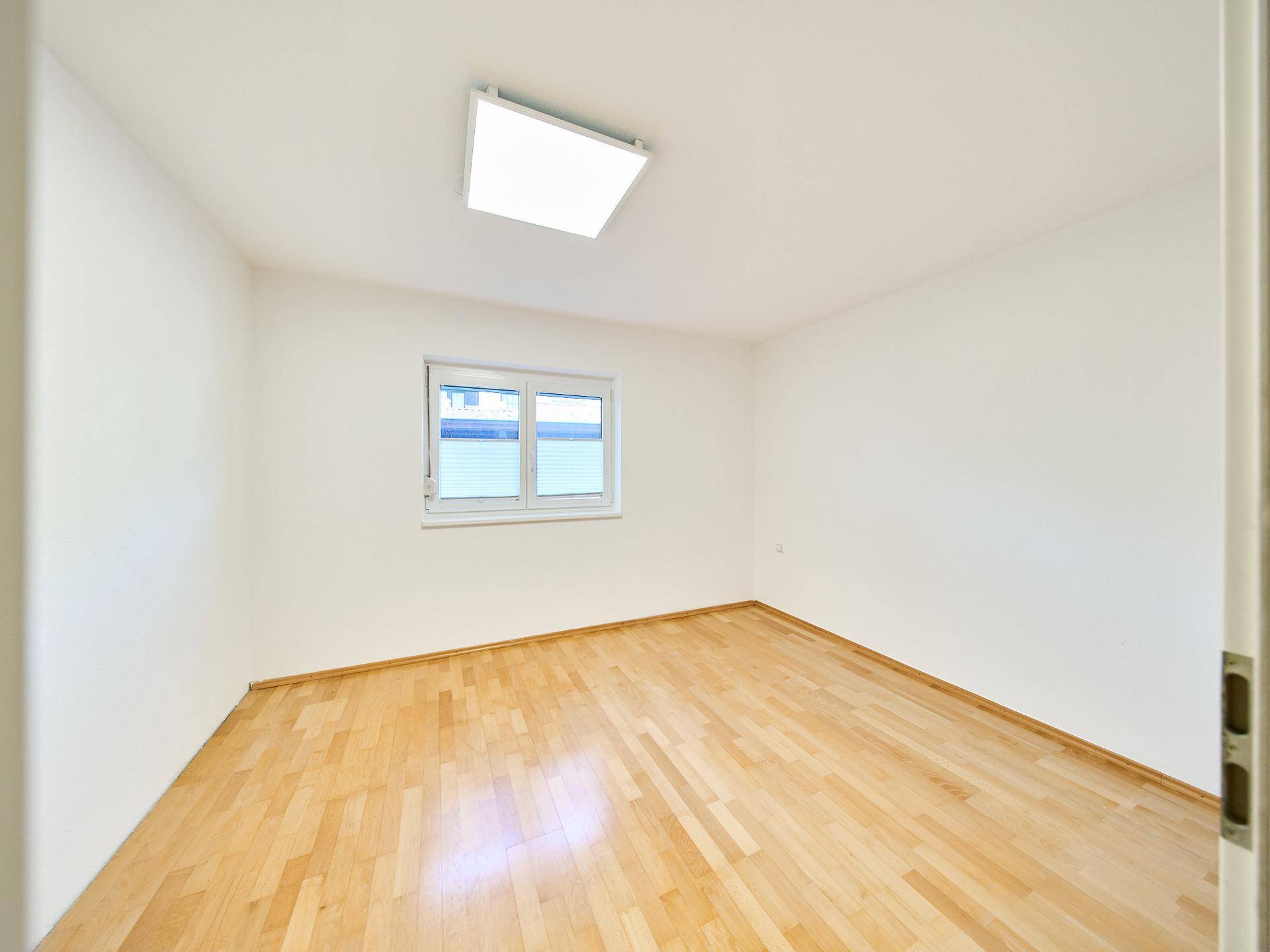 Helles Arbeitszimmer mit Holzboden und großem Fenster, ideal für Home-Office.