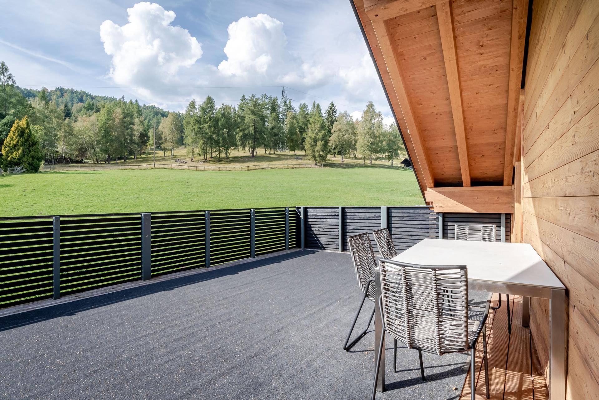 Große Terrasse mit Sitzgelegenheiten und weitem Blick über grüne Wiesen und Wälder.