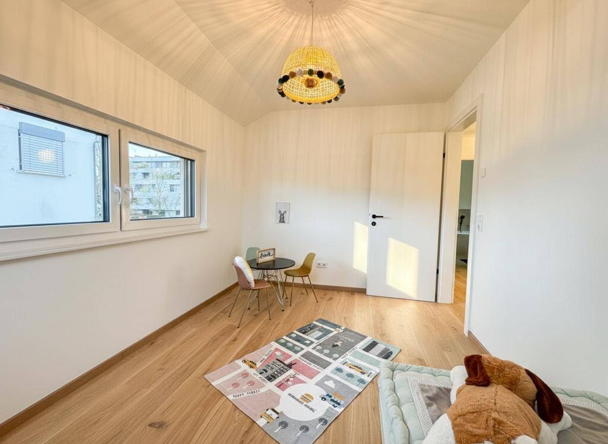 Freundliches Kinderzimmer mit Holzboden, kleinem Tisch und Stühlen, ideal zum Spielen und Lernen.