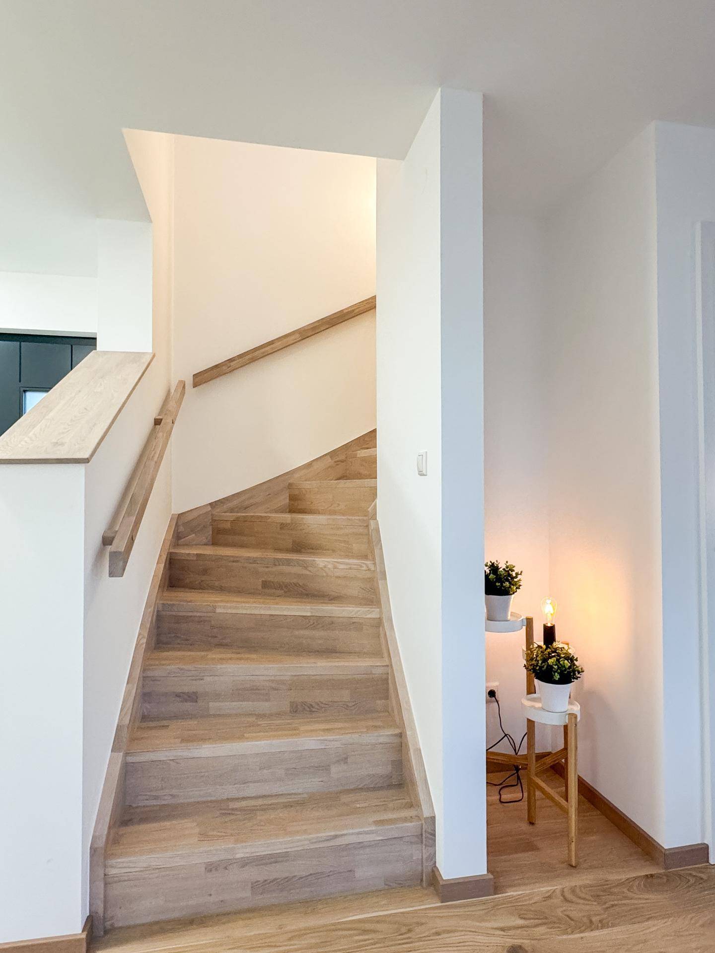 Helles Treppenhaus mit Holzstufen und passendem Geländer, das die Stockwerke elegant verbindet.
