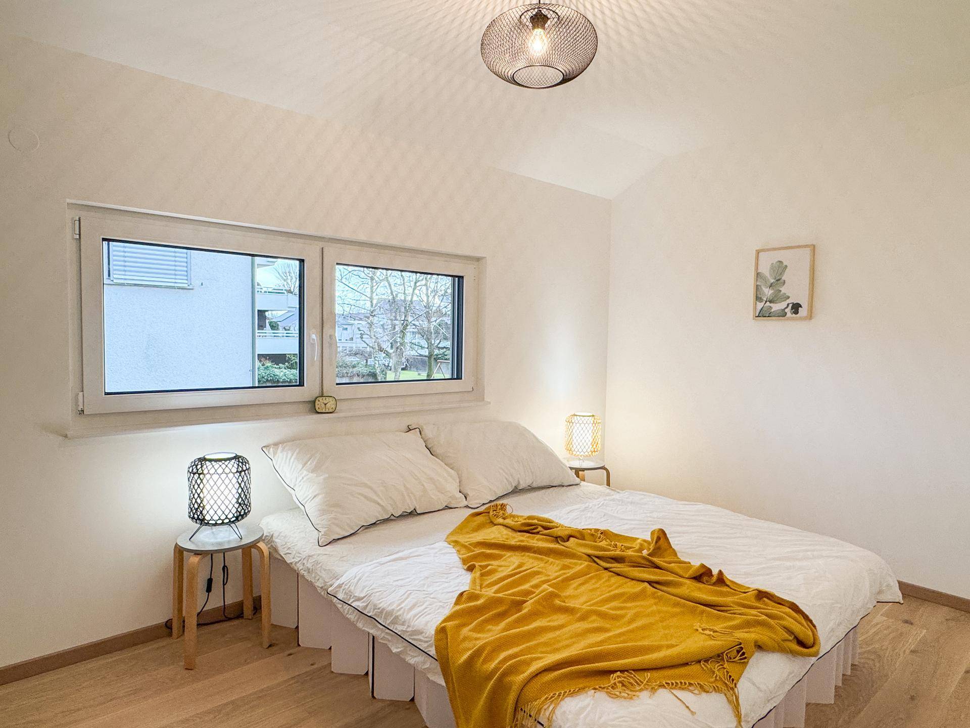 Gemütliches Schlafzimmer mit Doppelbett, hellem Holzboden und natürlichem Lichteinfall durch das Fenster.