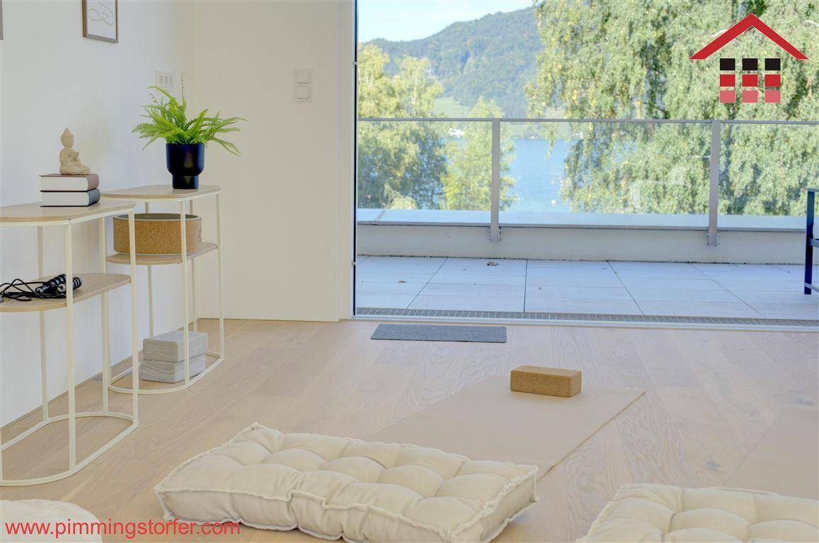 Heller Raum mit Holzboden und Zugang zu einem Balkon mit wunderschönem Seeblick.