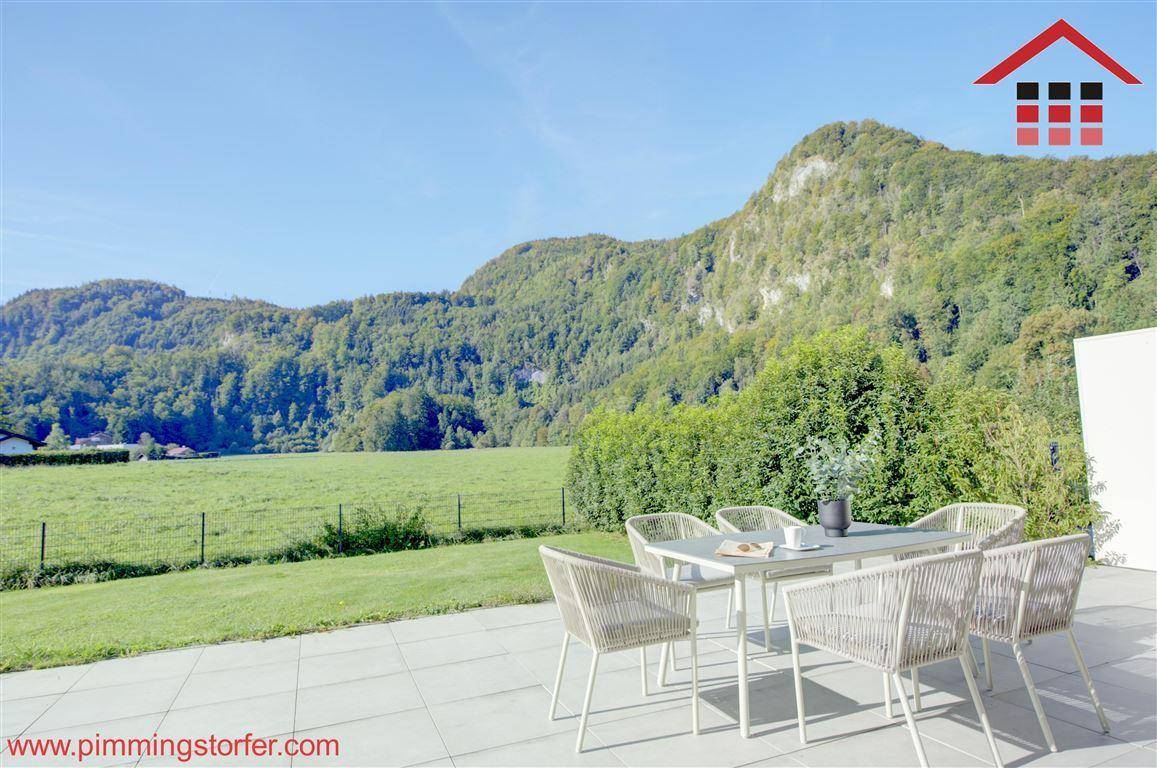 Moderne Terrasse mit bequemen Gartenmöbeln und weitem Blick auf grüne Felder und Berge.