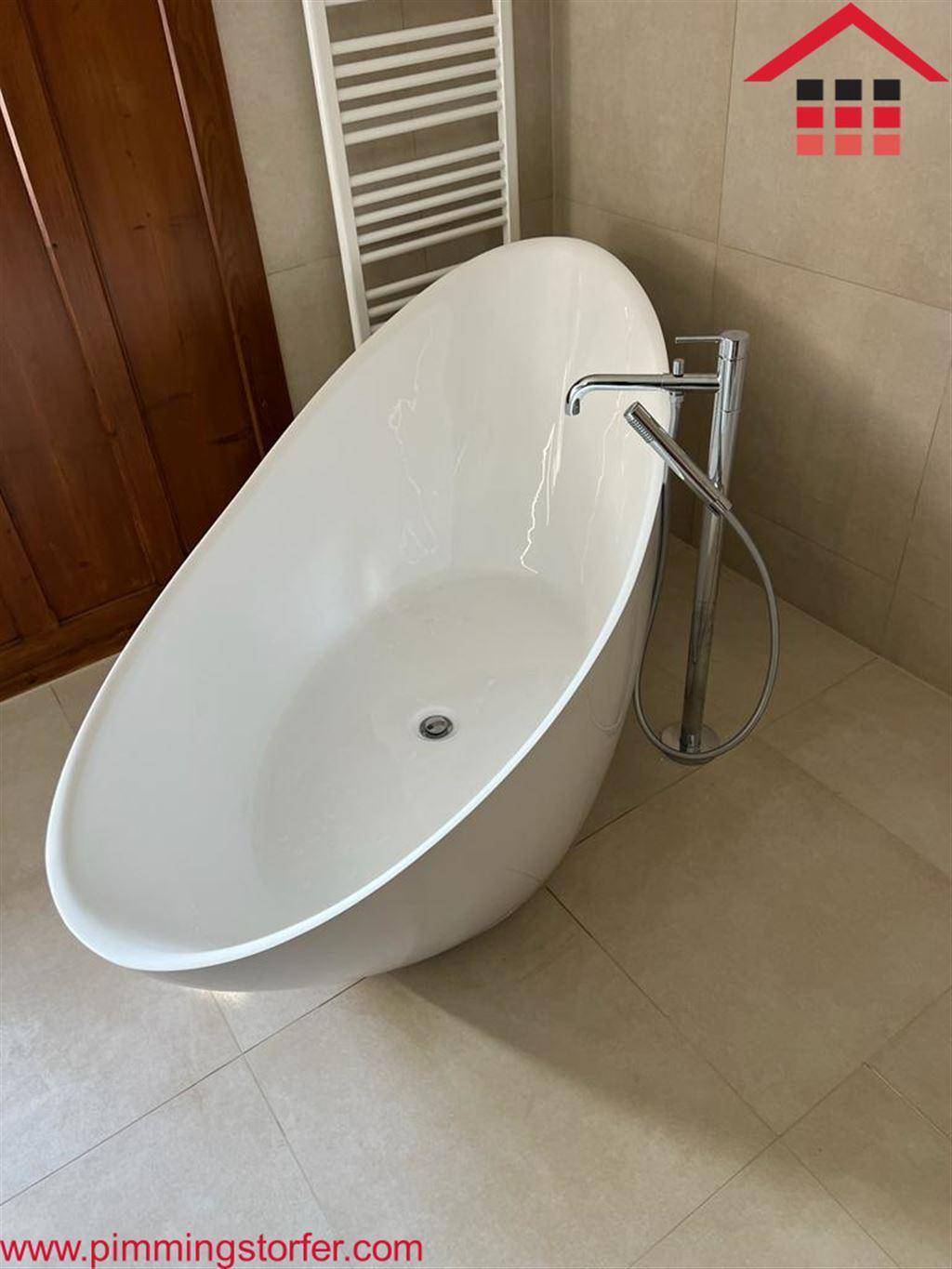 Modernes Badezimmer mit freistehender ovaler Badewanne und beheiztem Handtuchhalter an der Wand.