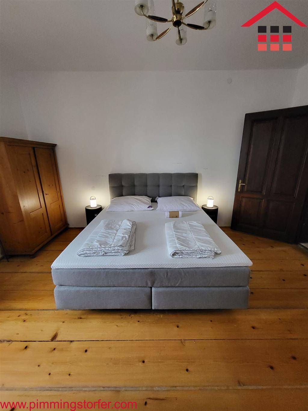 Gemütliches Schlafzimmer mit Holzdielenboden, Doppelbett und traditionellem Kleiderschrank.
