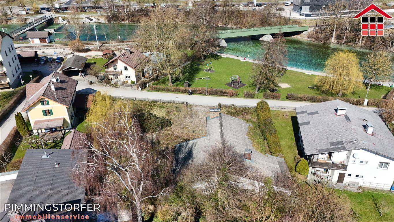 Luftaufnahme des Grundstücks mit umliegenden Häusern, einem Fluss und einem Spielplatz in der Nähe.