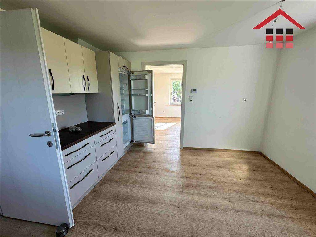 Funktionale Küche mit hellen Schränken und Laminatboden, offen zum angrenzenden Raum.