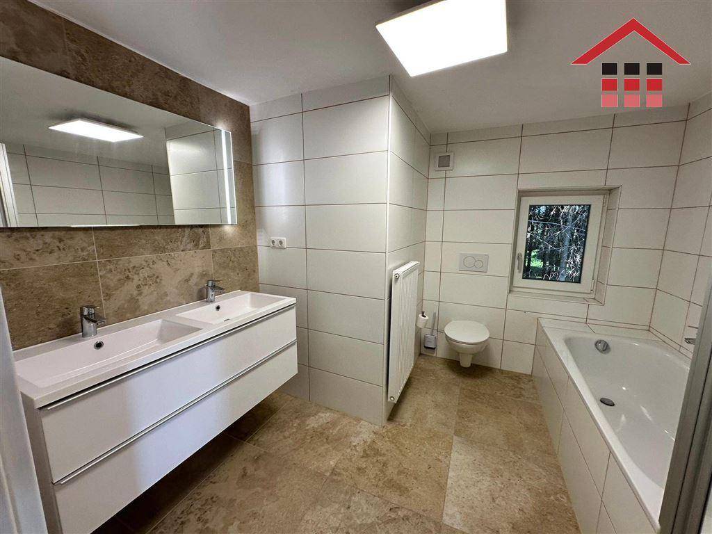Helles Badezimmer mit Doppelwaschbecken, großem Spiegel und modernen Fliesen.