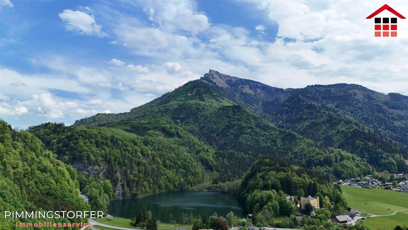 Atemberaubender Panoramablick auf eine Berglandschaft mit einem See und einem Dorf in der Ferne.