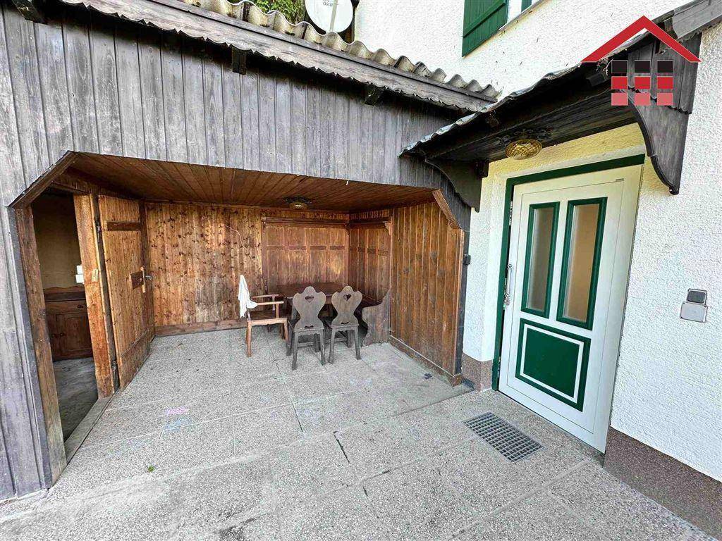 Überdachter Eingangsbereich mit rustikaler Sitzecke und Holztäfelung.