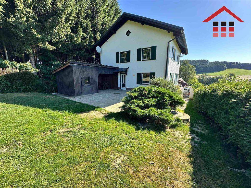 Freistehendes Haus mit großem Garten und angrenzendem Carport in ländlicher Umgebung.