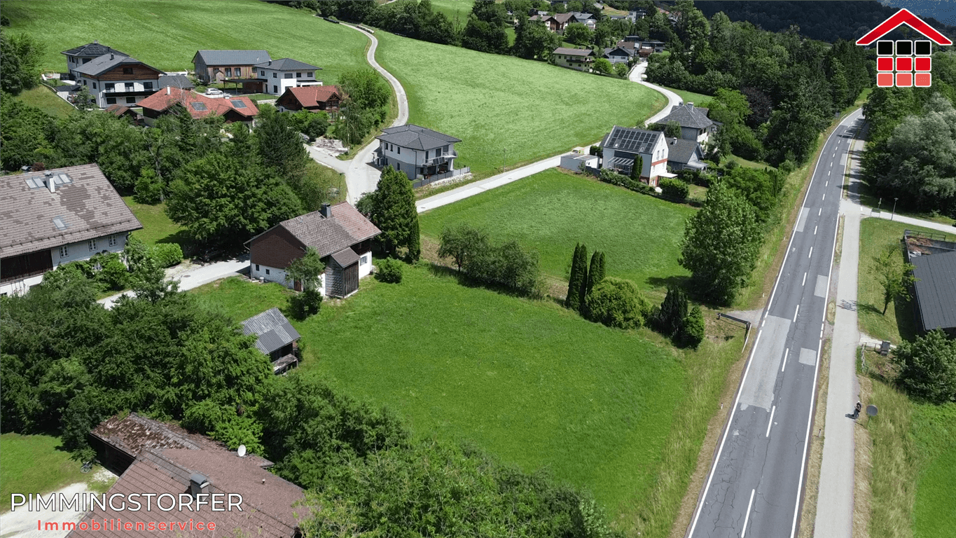Weitläufige Luftaufnahme eines Grundstücks mit Rasenfläche und angrenzender Straße in grüner Umgebung.