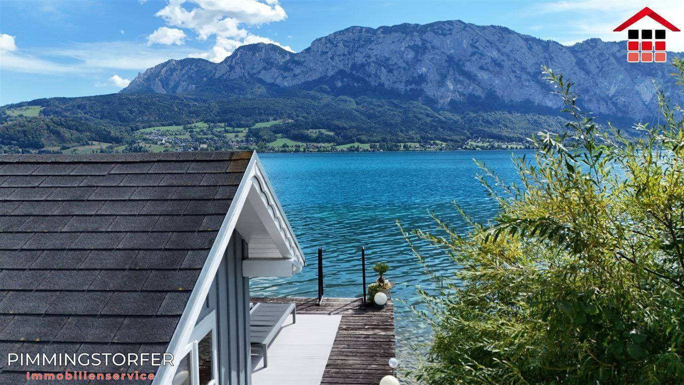 Holzsteg am Seeufer mit Blick auf das klare Wasser und die majestätischen Berge.