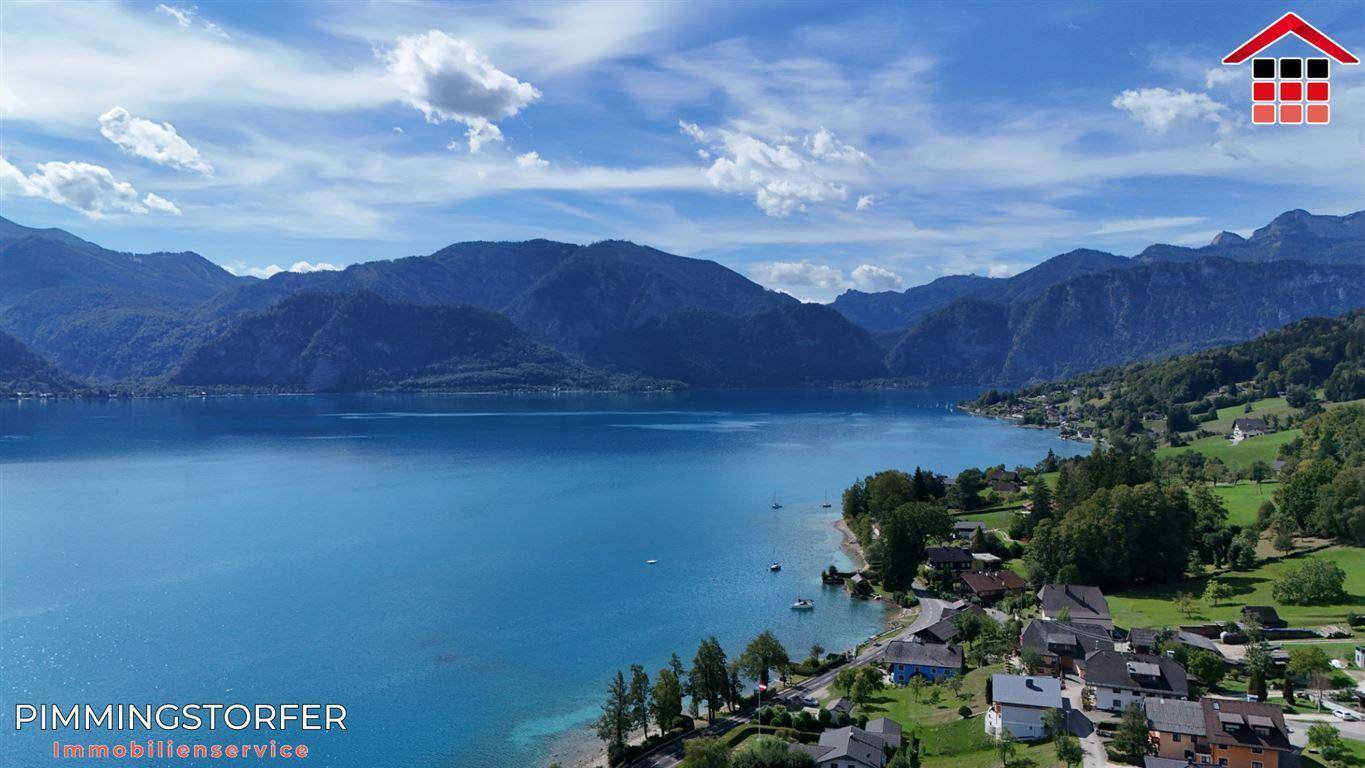 Panoramablick auf den malerischen See mit Uferbebauung und majestätischen Bergen im Hintergrund.