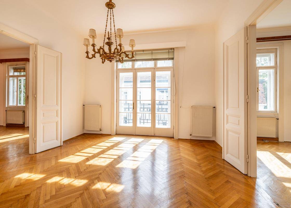 Helles Wohnzimmer mit Fischgrätparkett, hohen Fenstern und viel natürlichem Sonnenlicht.