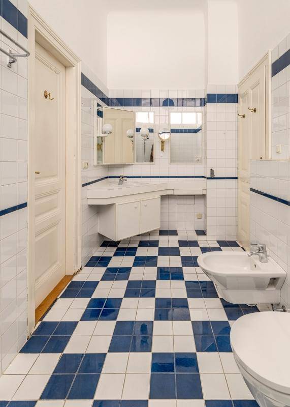 Badezimmer mit blau-weiß karierten Fliesen, Bidet und einem einzelnen Waschbecken.