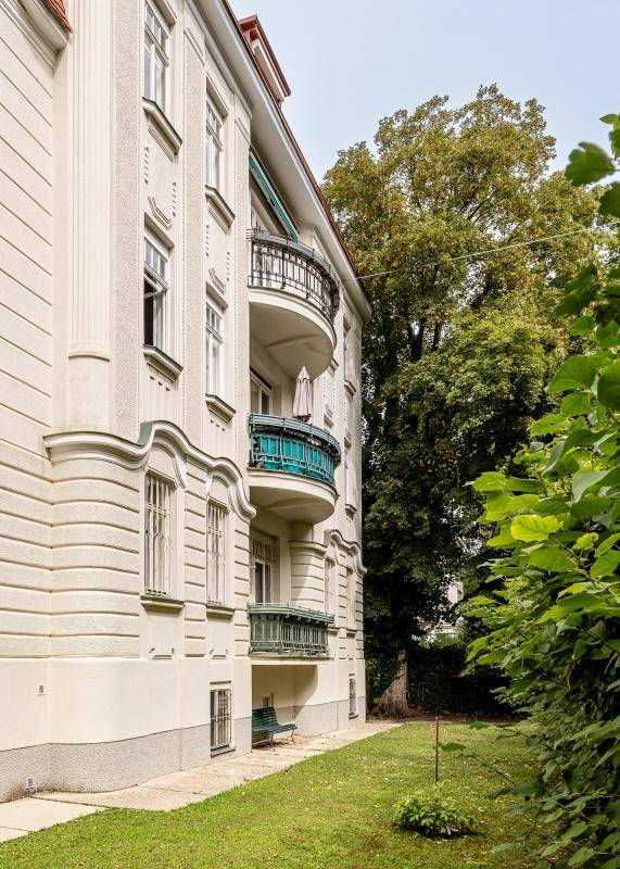 Gepflegter Gartenbereich neben dem Gebäude mit grüner Rasenfläche und Bäumen.