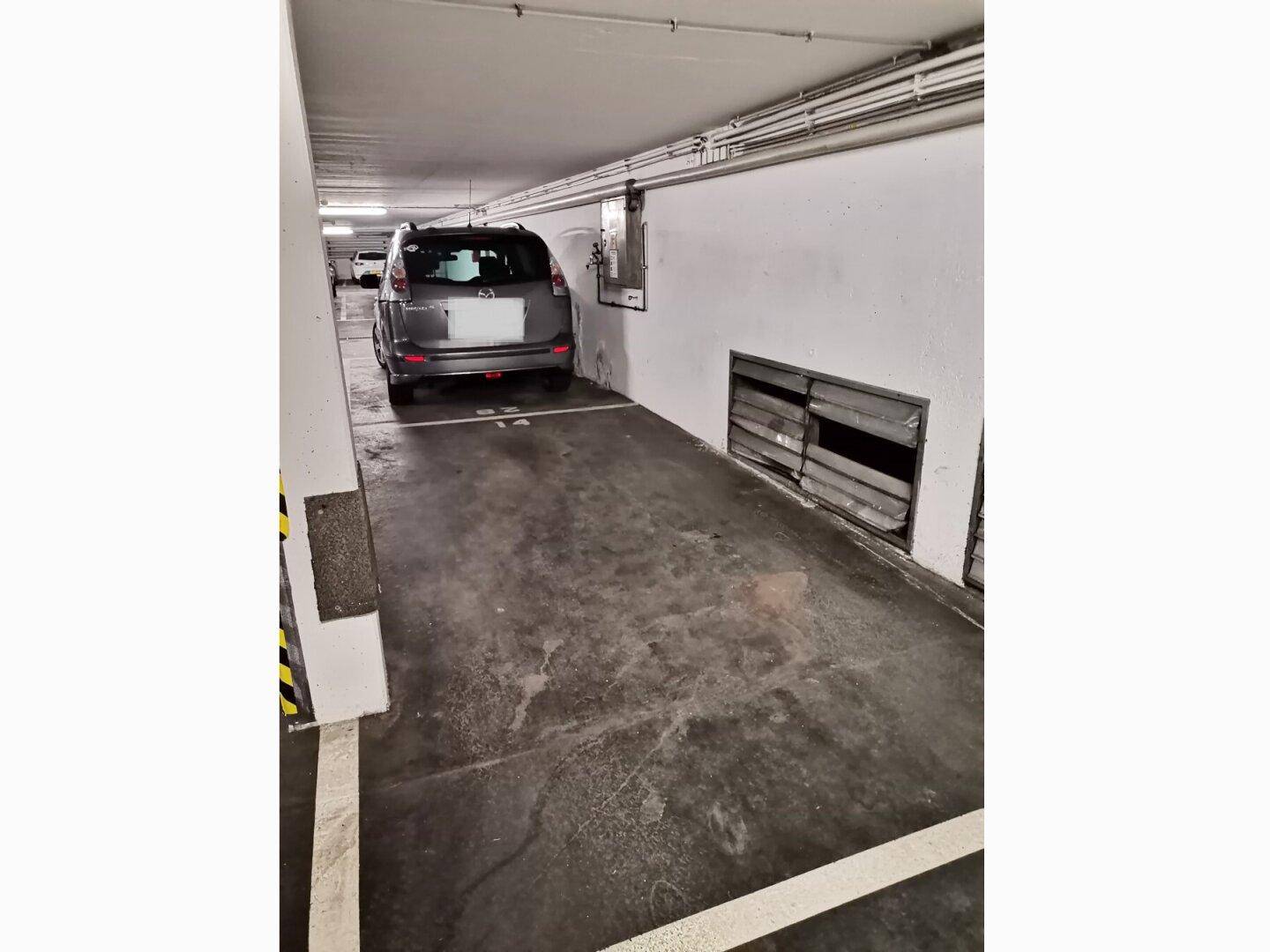Einzelner Stellplatz in einer Tiefgarage mit Betonboden und weiß gestrichenen Wänden.