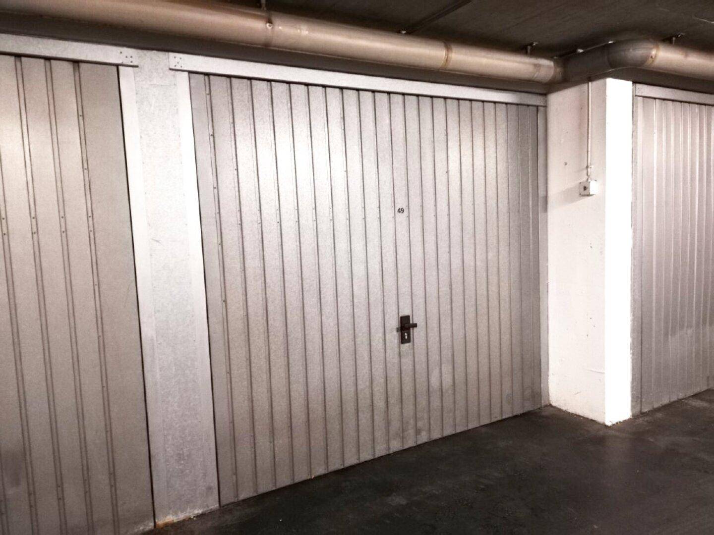 Einzelne Garagenbox mit Metalltor in einer Tiefgarage.