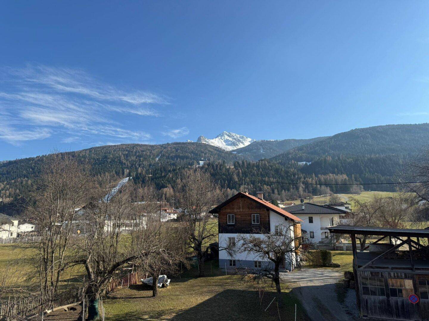 Weitläufiger Blick auf die Berge und umliegende Häuser unter klarem blauem Himmel.