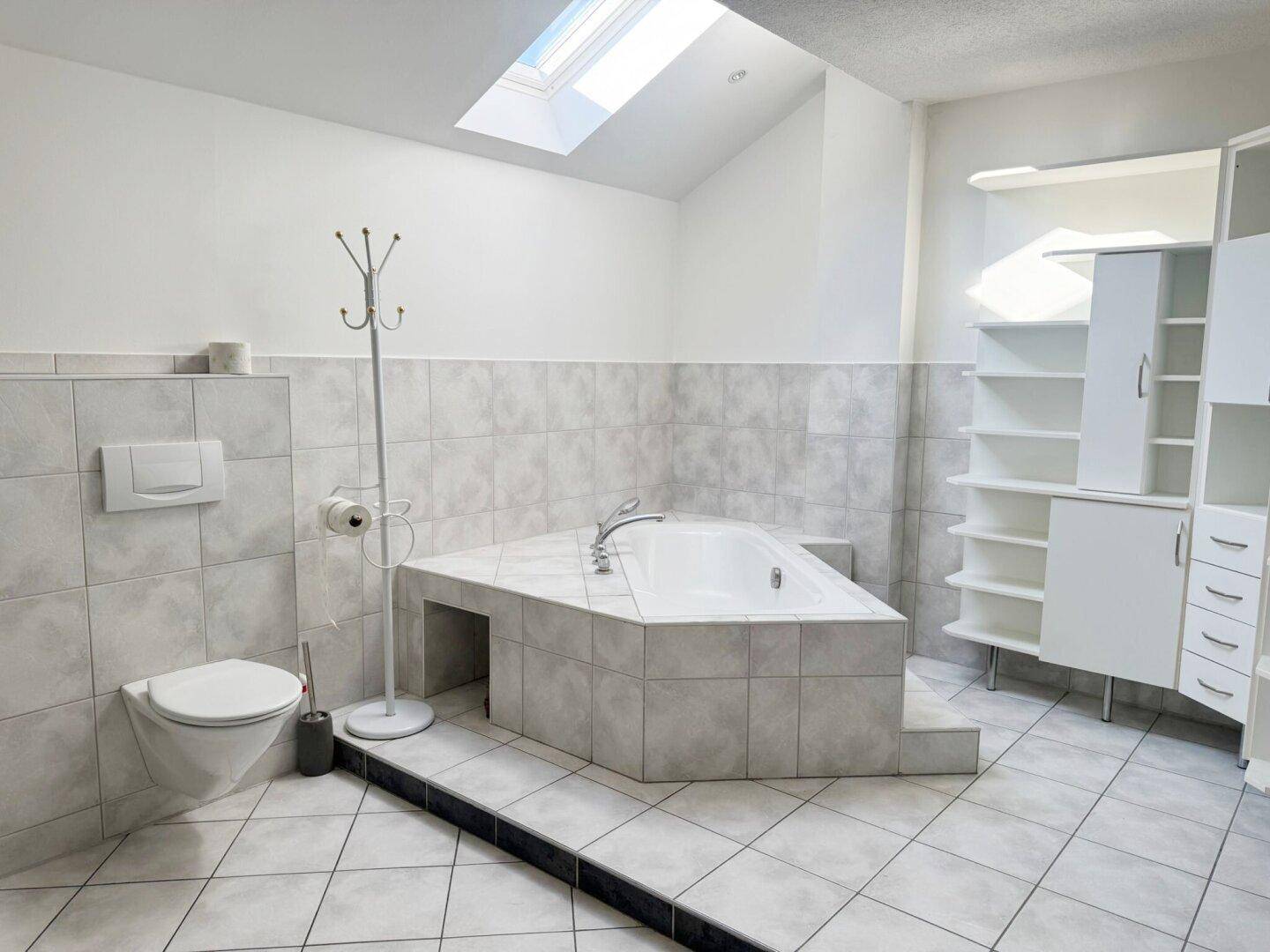 Geräumiges Badezimmer im Dachgeschoss mit Eckbadewanne, Toilette und Dachfenster.