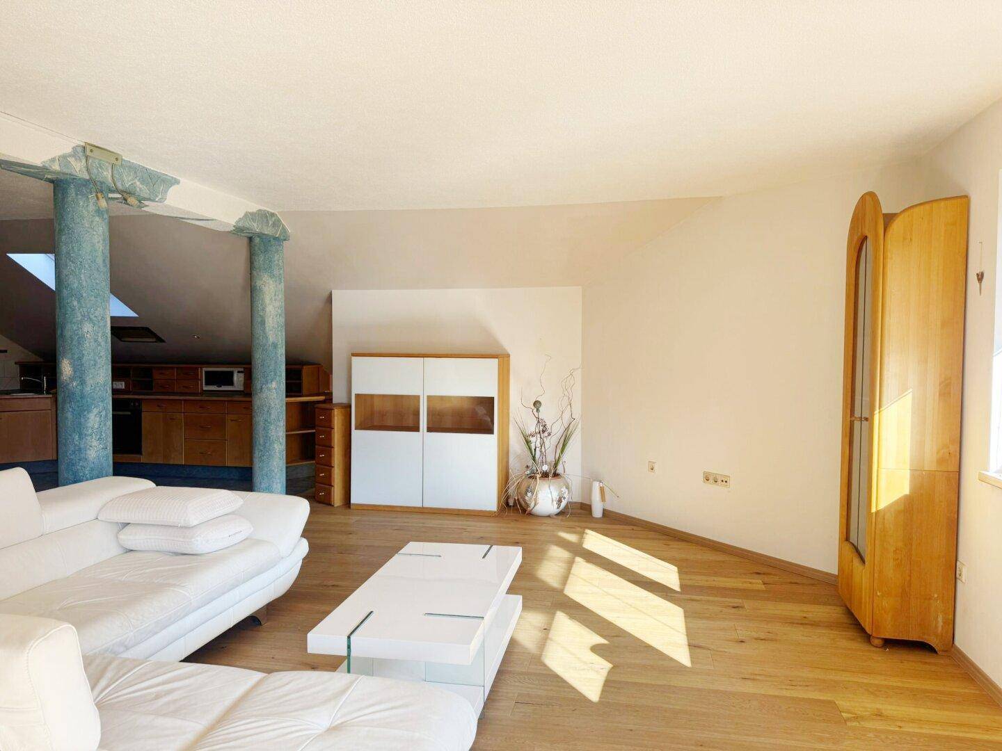 Heller Wohnbereich mit Holzboden, weißem Sofa und modernen Möbeln.