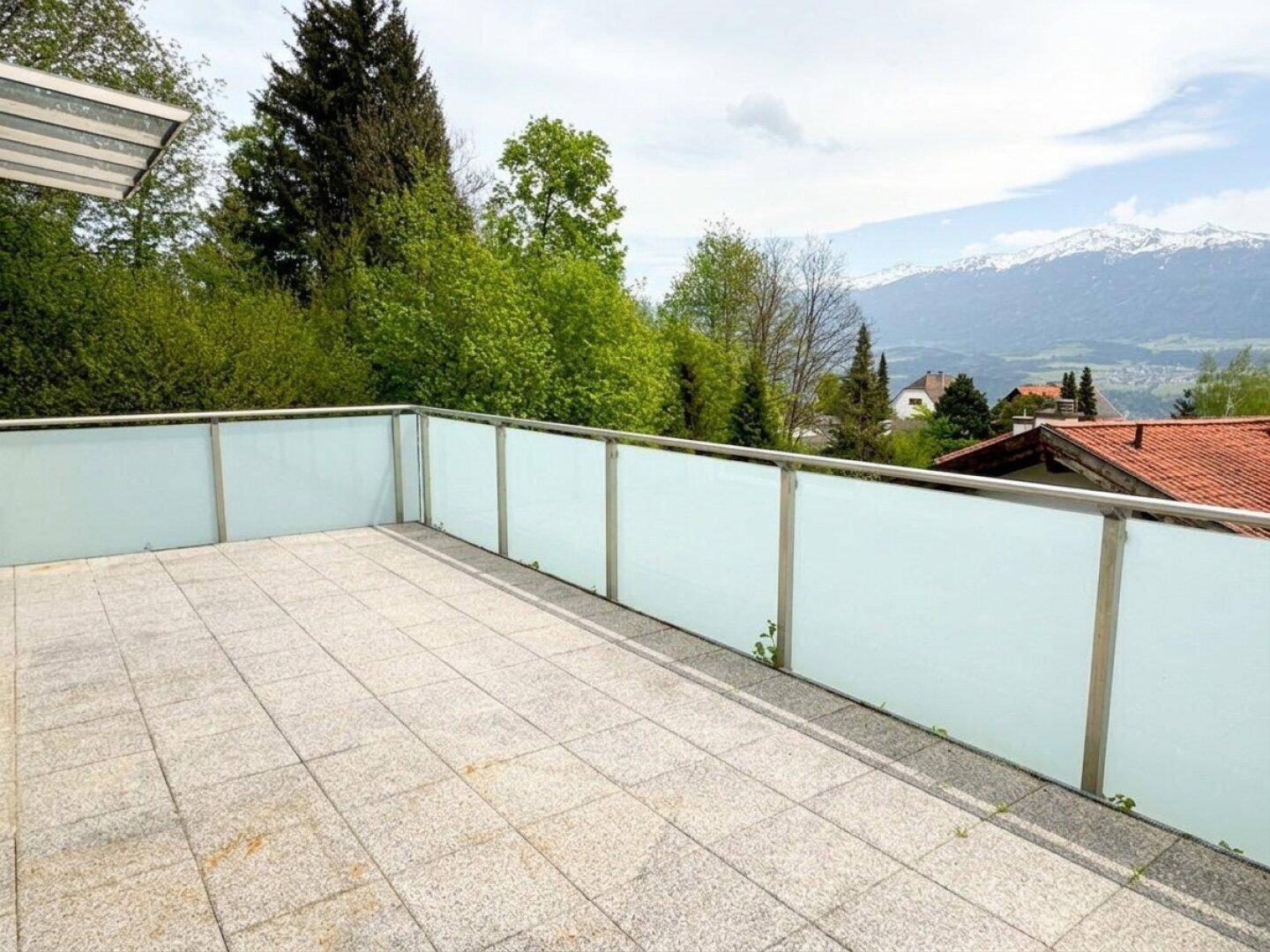 Geräumiger Balkon mit Fliesen und moderner Glasbrüstung, bietet einen Panoramablick auf die Berge.