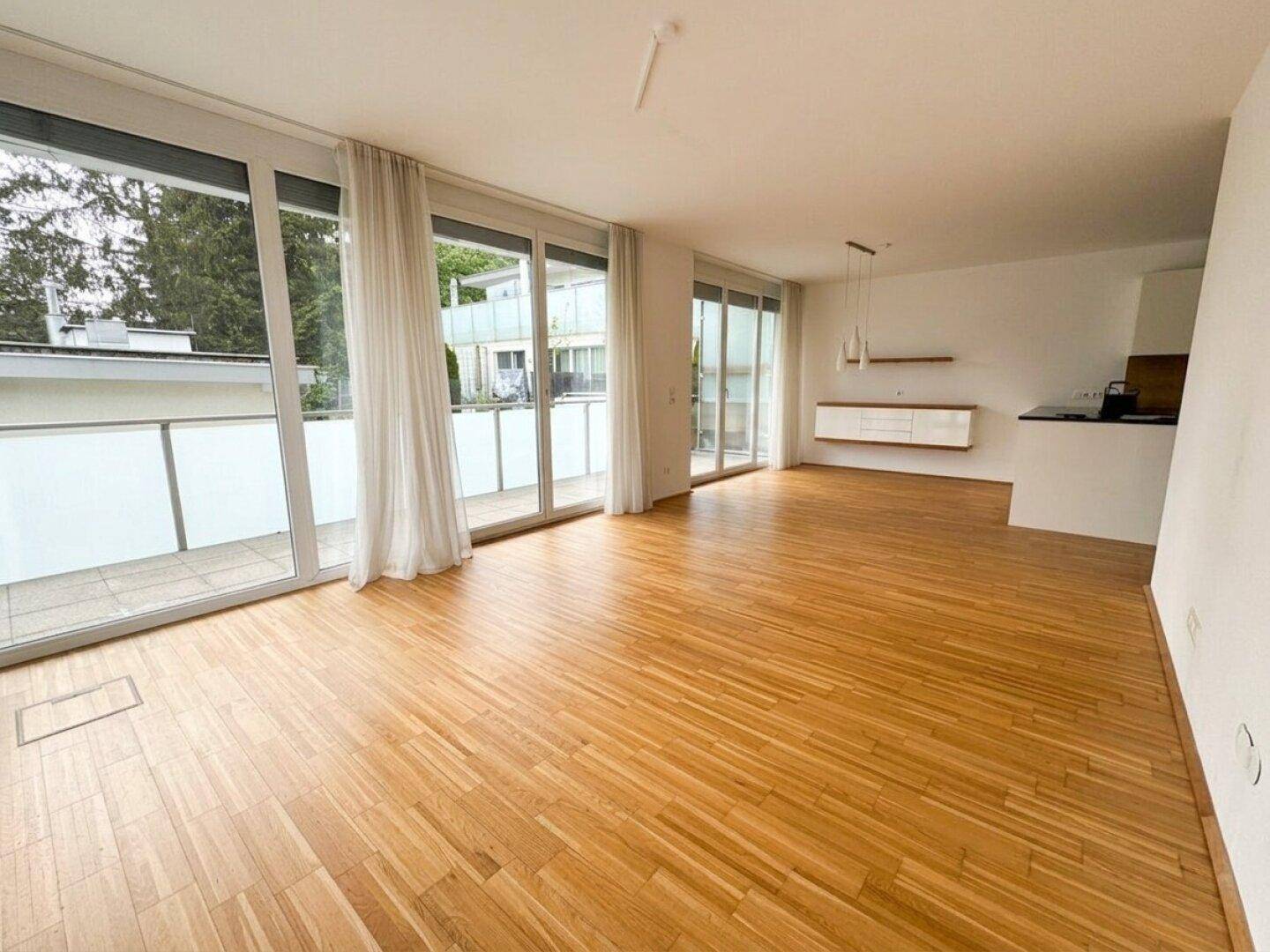 Geräumiger Wohnbereich mit viel Tageslicht, Parkettboden und Blick ins Grüne.