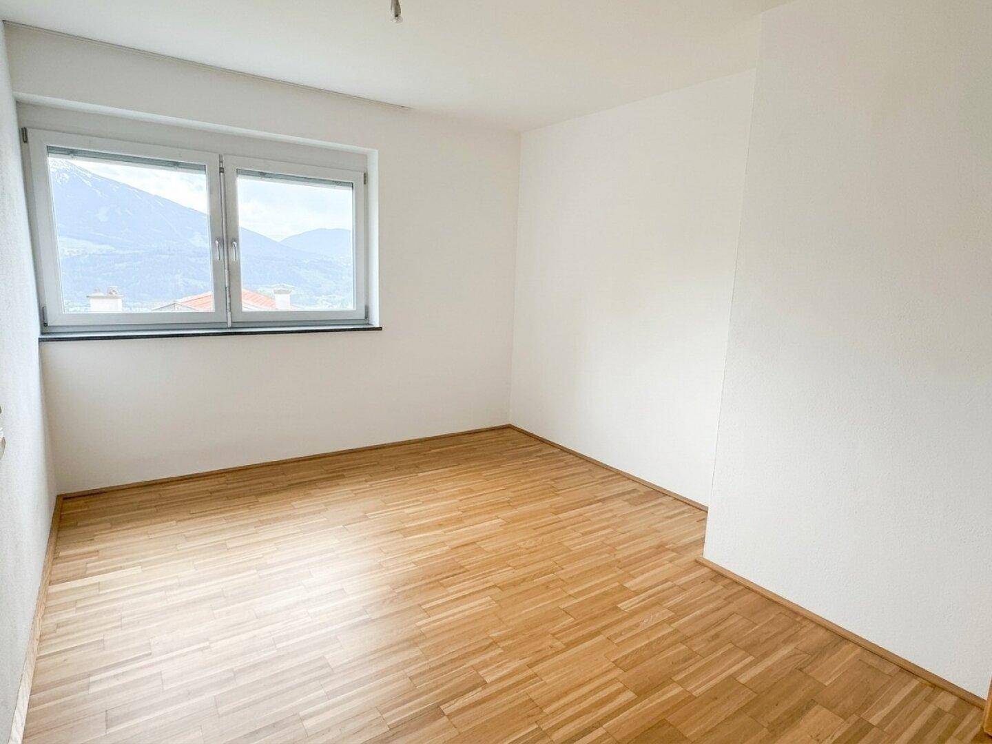 Helles Schlafzimmer mit Parkettboden und Fenster, das einen schönen Bergblick bietet.