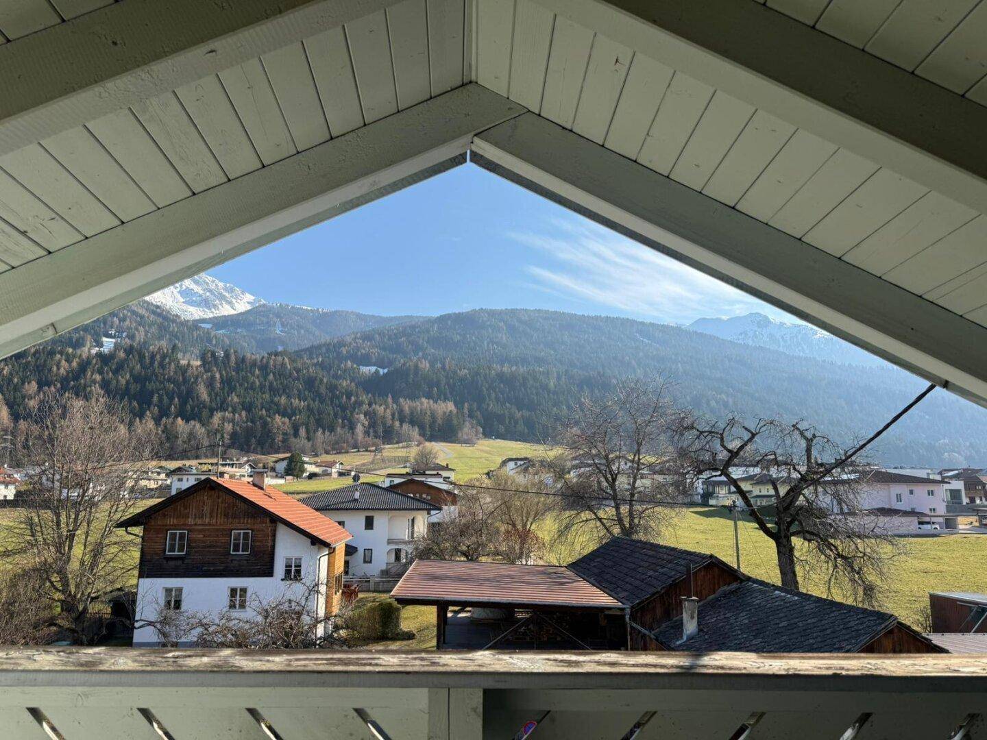Panoramablick auf eine malerische Berglandschaft mit Häusern und grünen Tälern.