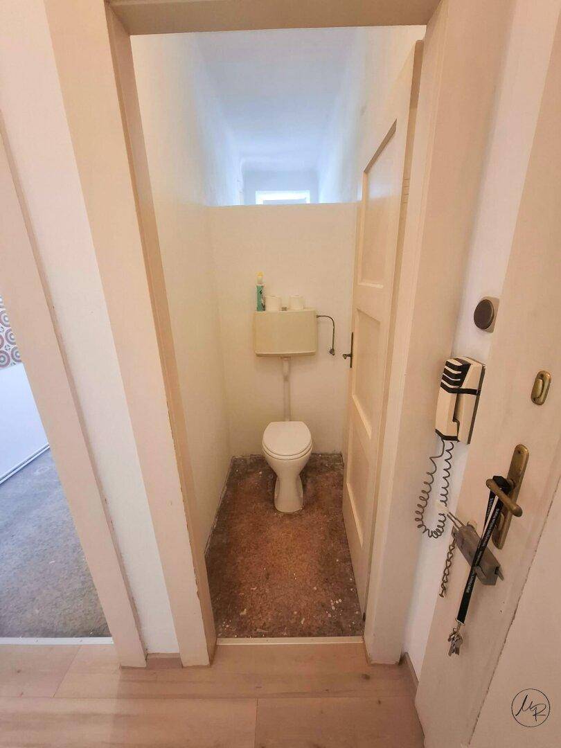 Kleines separates WC mit Toilette und Spülkasten, funktional und einfach gehalten.