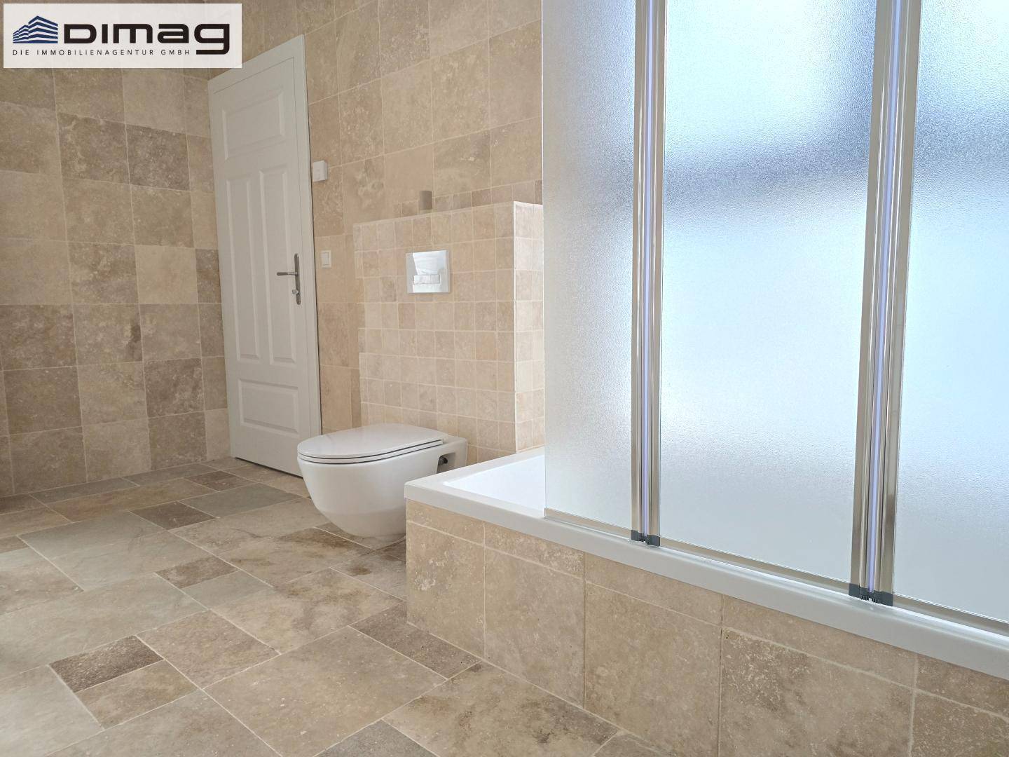 Modernes Badezimmer mit beigefarbenen Fliesen, Badewanne mit Duschwand und wandhängendem WC.