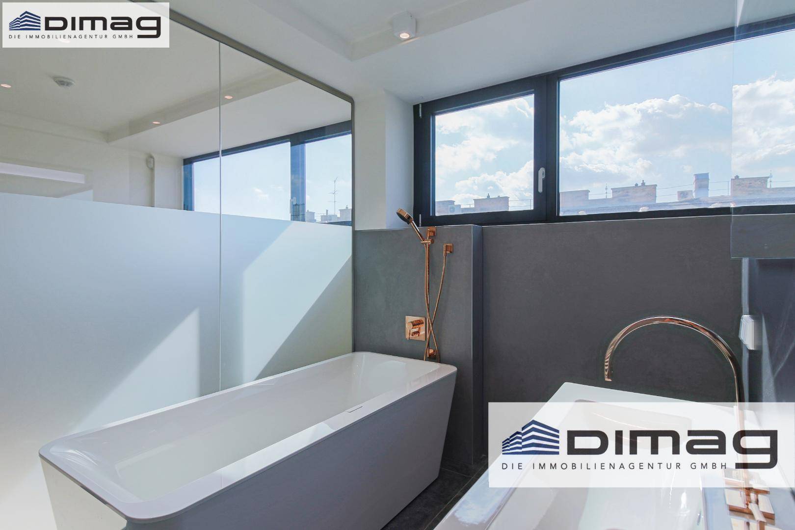 Modernes Badezimmer mit Badewanne und Doppelwaschbecken, durch eine Glaswand vom Schlafbereich getrennt.