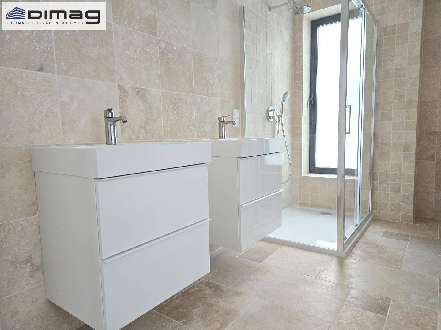 Modernes Badezimmer mit Doppelwaschtisch, ebenerdiger Dusche und beigefarbenen Fliesen.
