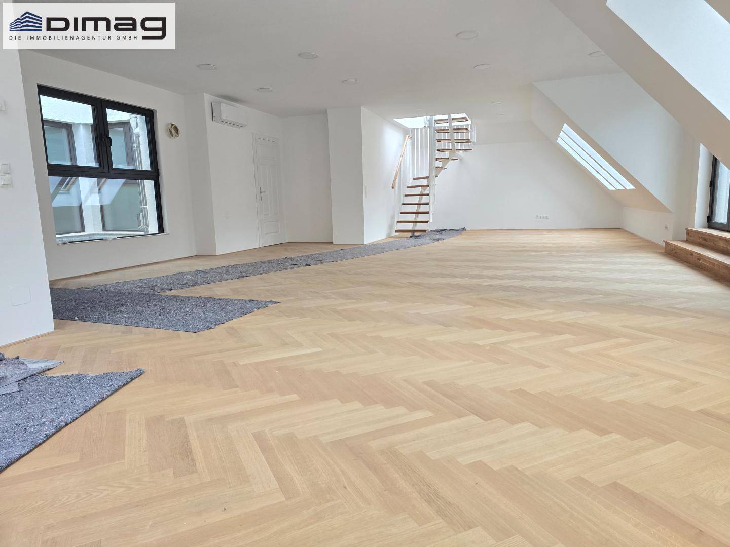 Weitläufiger Wohnbereich mit neuem Fischgrätparkett, moderner Treppe und viel Tageslicht.