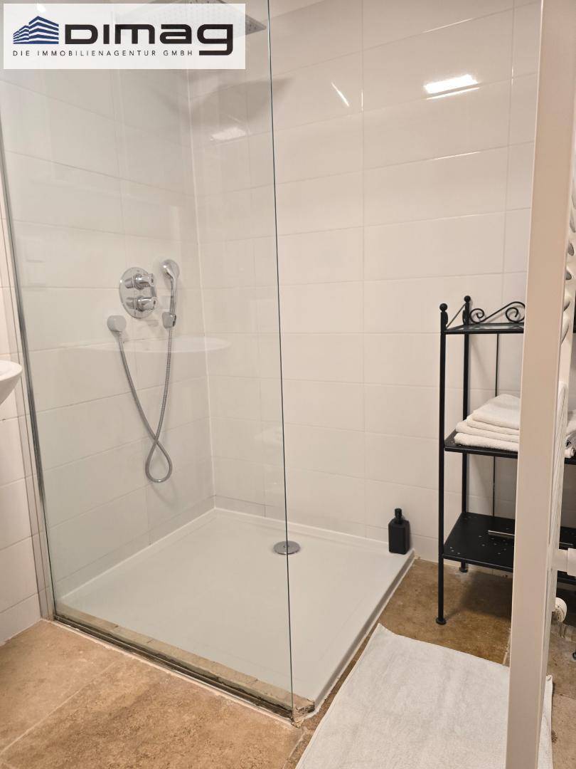 Modernes Badezimmer mit begehbarer Dusche und weißen Fliesen.
