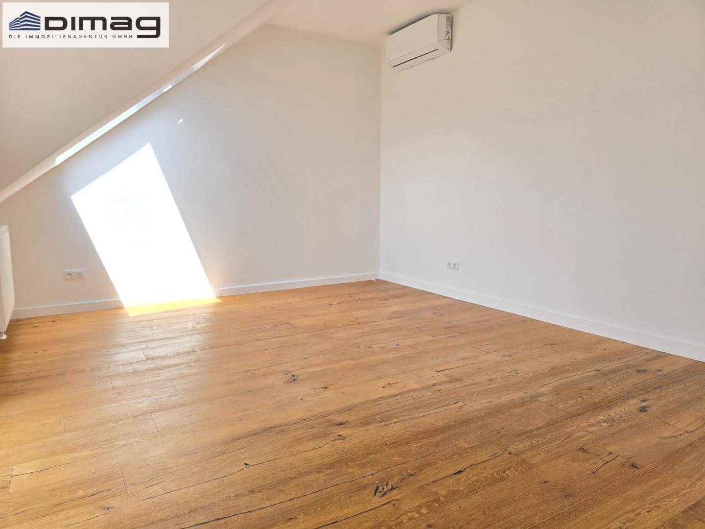 Helles Zimmer mit Holzboden und schrägem Dachfenster, ideal für ein Schlafzimmer.