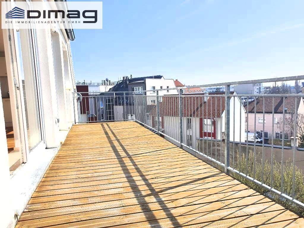 Geräumiger Balkon mit Holzbelag und Metallgeländer, der einen Blick auf die umliegende Stadt bietet.