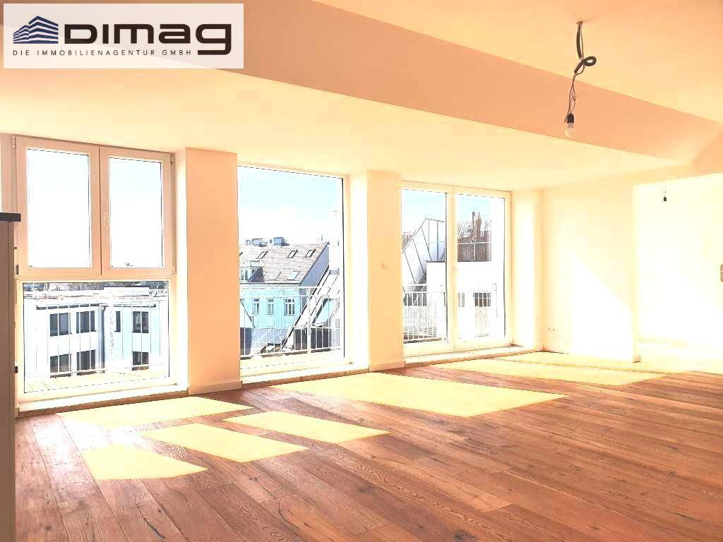 Geräumiger Wohnbereich mit Holzboden und großen Fenstern, die viel Tageslicht hereinlassen und eine weite Aussicht ermöglichen.