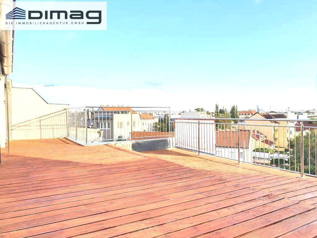Große Dachterrasse mit Holzbelag und Metallgeländer, die einen weiten Blick über die Stadt bietet.