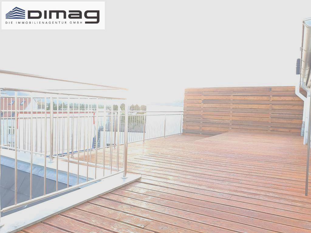 Geräumige Dachterrasse mit Holzbelag, Metallgeländer und einer hölzernen Sichtschutzwand.